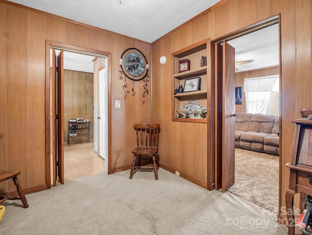 hallway with built in features, wood walls, and carpet