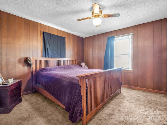 carpeted bedroom with wooden walls, a ceiling fan, baseboards, and a textured ceiling