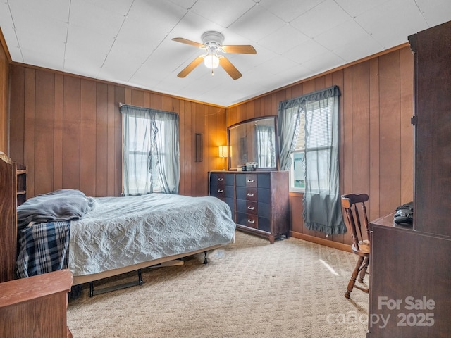 bedroom featuring wooden walls, carpet floors, and ceiling fan