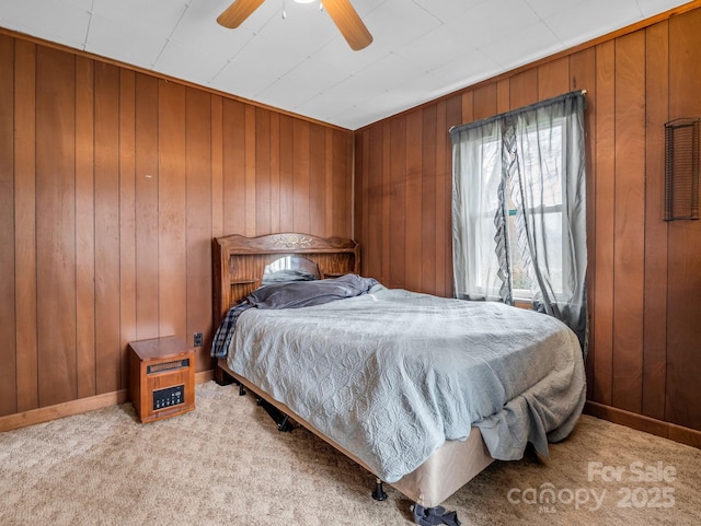 bedroom featuring light carpet, wood walls, and ceiling fan