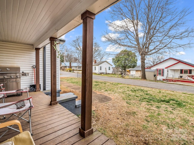 wooden terrace with grilling area, a residential view, and a lawn