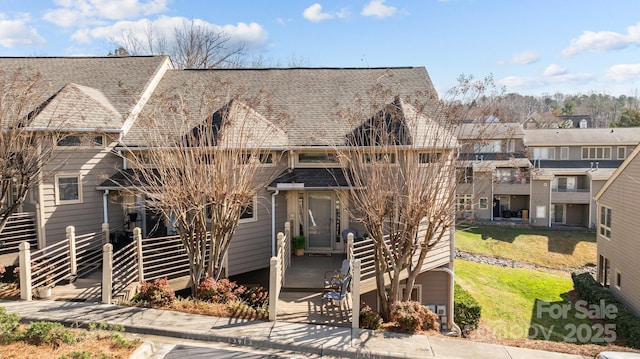 view of front of property with roof with shingles and fence