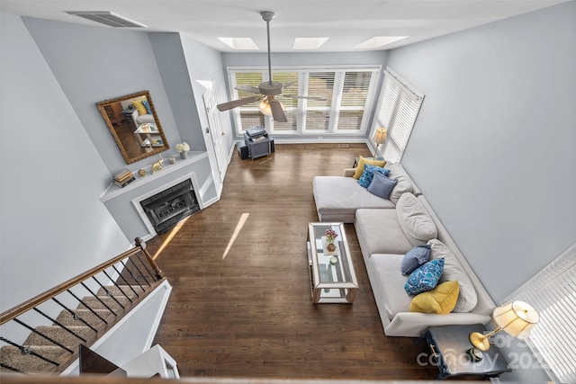 living area featuring visible vents, a ceiling fan, wood finished floors, a skylight, and a fireplace