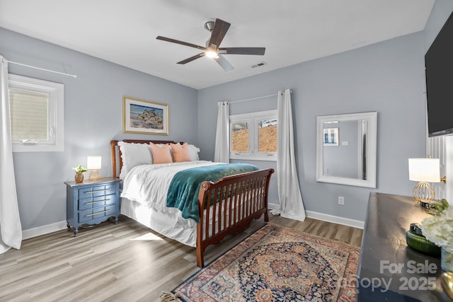 bedroom featuring visible vents, ceiling fan, baseboards, and wood finished floors