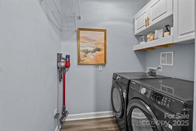 laundry area featuring visible vents, baseboards, washer and clothes dryer, wood finished floors, and cabinet space