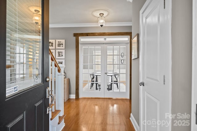 entryway featuring light wood finished floors, stairway, french doors, and ornamental molding