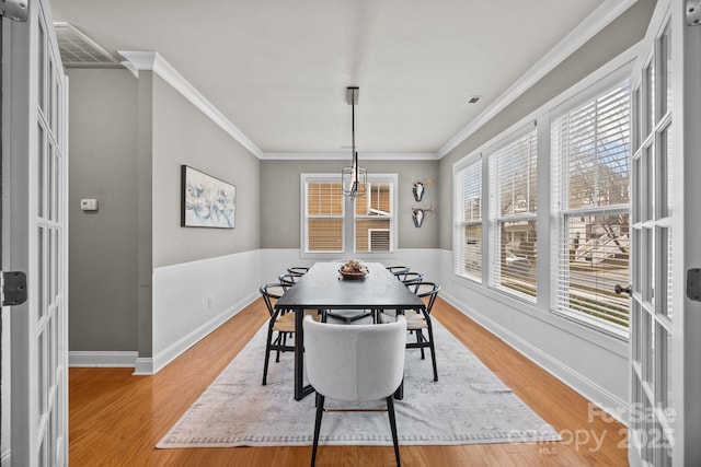 dining space with visible vents, baseboards, crown molding, and light wood finished floors