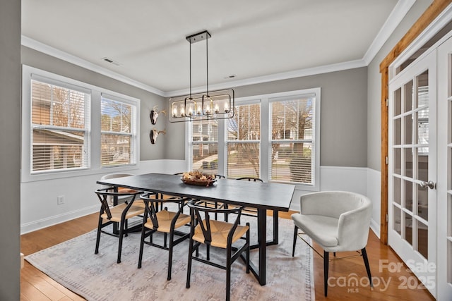 dining room with visible vents, a notable chandelier, wood finished floors, and crown molding