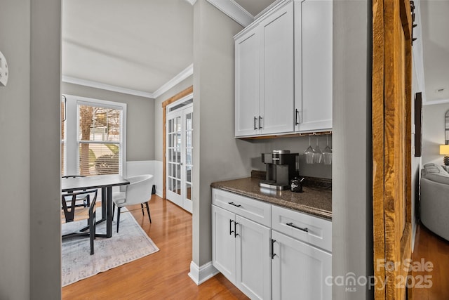 bar with light wood finished floors, french doors, and crown molding