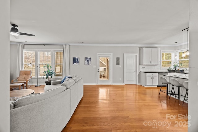 living area with light wood-style flooring, a ceiling fan, and baseboards