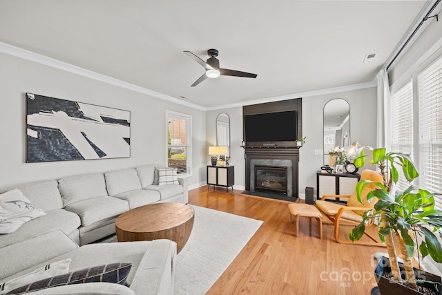 living room featuring ceiling fan, wood finished floors, plenty of natural light, and ornamental molding