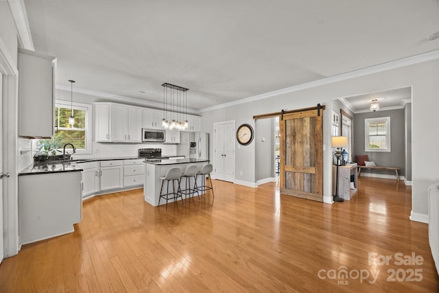 kitchen with a sink, a barn door, dark countertops, and stainless steel appliances