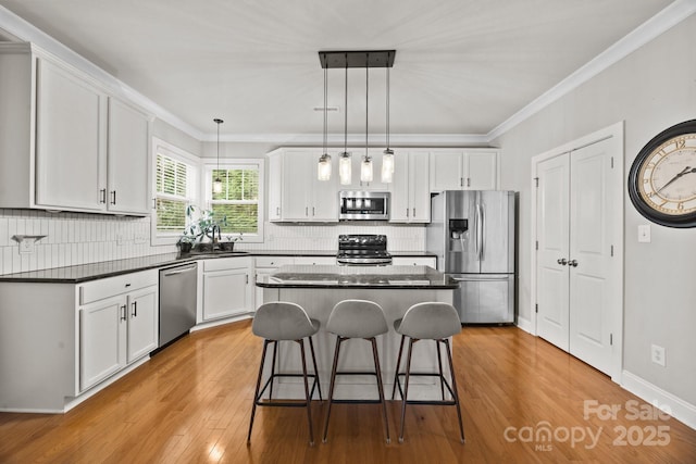 kitchen featuring a breakfast bar, white cabinets, light wood-type flooring, and stainless steel appliances