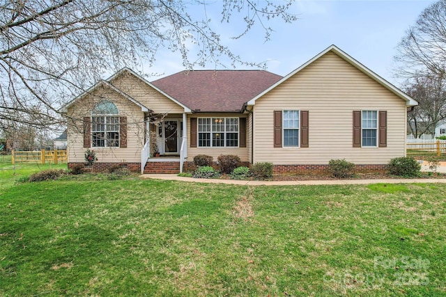 ranch-style home featuring a front lawn, fence, and roof with shingles