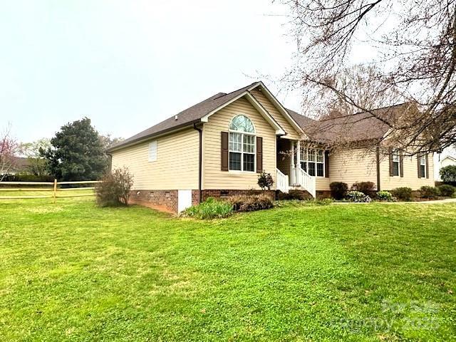 view of front of home with a front yard, fence, and crawl space