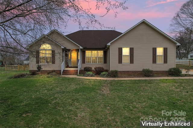 ranch-style home with a lawn and fence