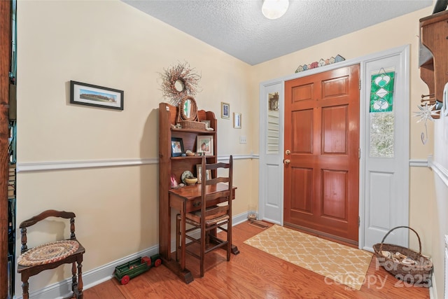 entryway with wood finished floors, baseboards, and a textured ceiling