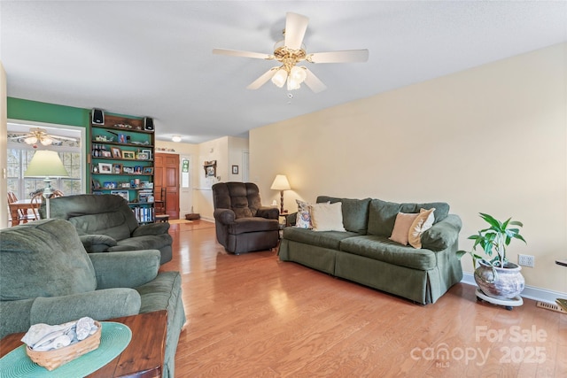 living area with visible vents, baseboards, light wood-style floors, and ceiling fan