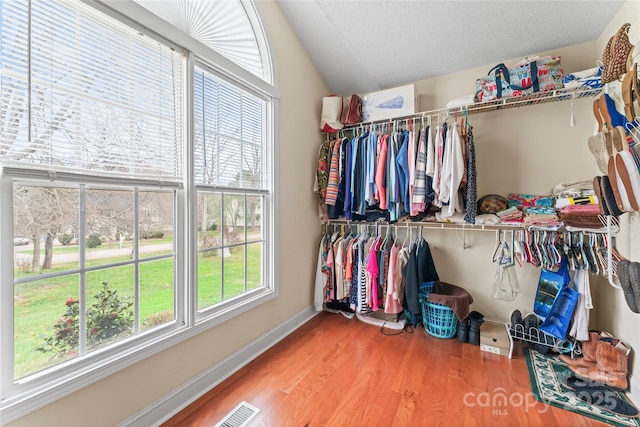 walk in closet with visible vents, lofted ceiling, and wood finished floors