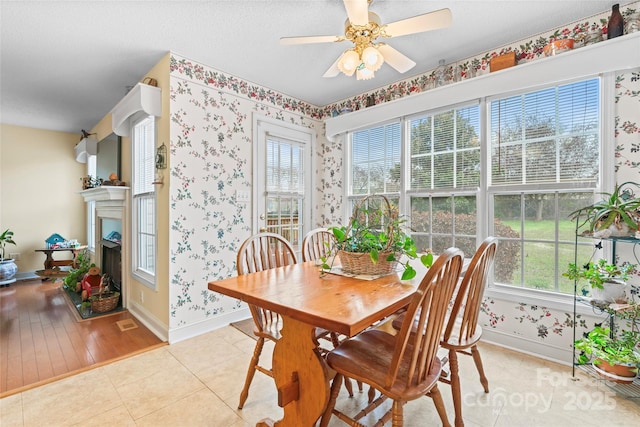 dining space featuring a wealth of natural light, wallpapered walls, a ceiling fan, and light tile patterned flooring