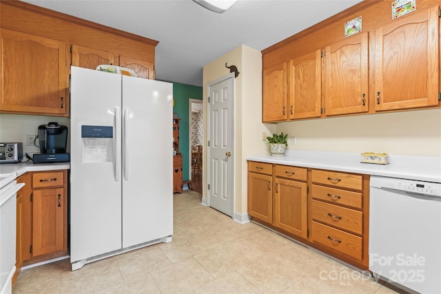 kitchen featuring white appliances, light countertops, and brown cabinets