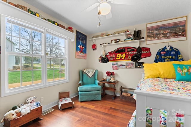 bedroom with visible vents, a ceiling fan, a textured ceiling, wood finished floors, and baseboards