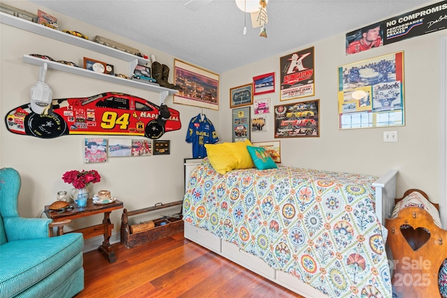 bedroom with ceiling fan, wood finished floors, and a textured ceiling