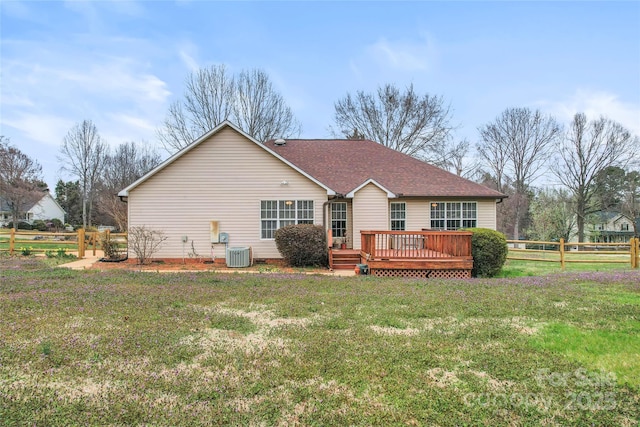 rear view of house with central air condition unit, roof with shingles, a fenced backyard, a yard, and a deck