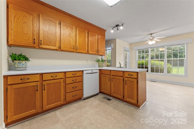 1278 Gracebrook Dr, Salisbury, NC 28147 - kitchen featuring dishwasher, a peninsula, brown cabinets, light countertops, and a textured ceiling