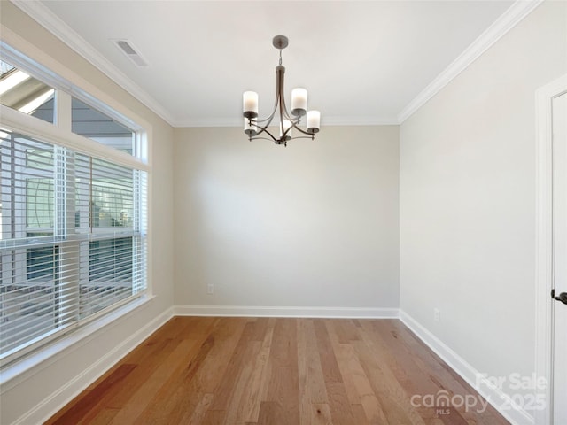 empty room with baseboards, visible vents, an inviting chandelier, light wood-style flooring, and ornamental molding