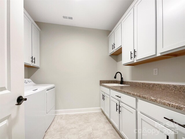 clothes washing area with baseboards, visible vents, cabinet space, a sink, and washer and clothes dryer