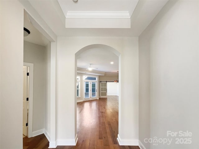 hall with dark wood finished floors, baseboards, arched walkways, and ornamental molding