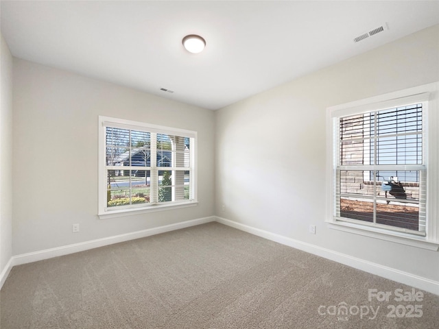 carpeted empty room with visible vents and baseboards