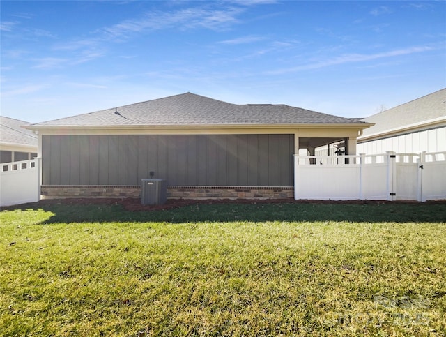 view of home's exterior with central air condition unit, roof with shingles, a yard, and fence