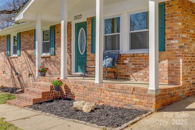 property entrance featuring brick siding and a porch