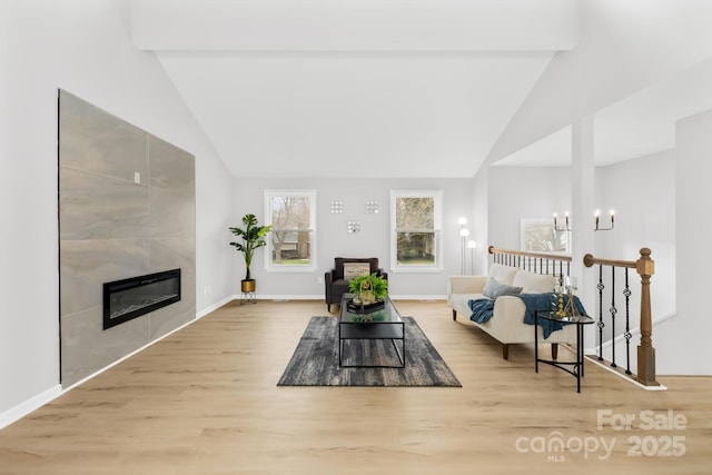 living room with baseboards, high vaulted ceiling, wood finished floors, and a tile fireplace