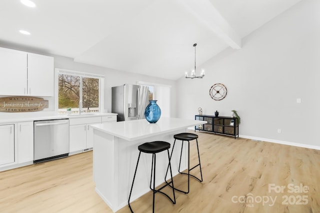 kitchen with a breakfast bar area, lofted ceiling with beams, light countertops, appliances with stainless steel finishes, and white cabinets