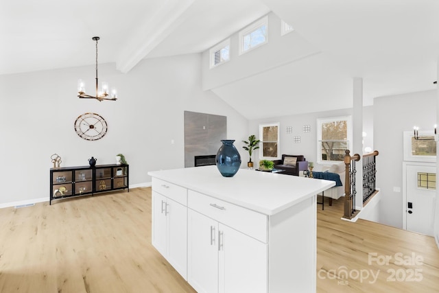 kitchen featuring a notable chandelier, beamed ceiling, a center island, and light wood-style floors