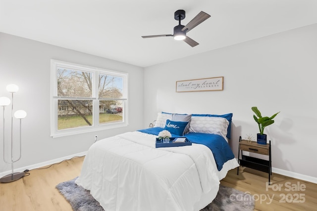 bedroom featuring baseboards, wood finished floors, and a ceiling fan