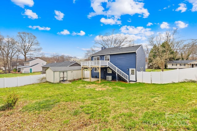 rear view of house featuring a shed, stairway, a lawn, a fenced backyard, and an outbuilding