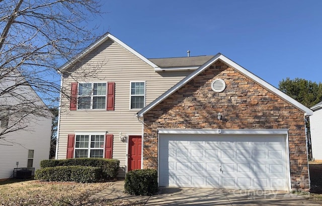 traditional-style home with central air condition unit, stone siding, a garage, and driveway