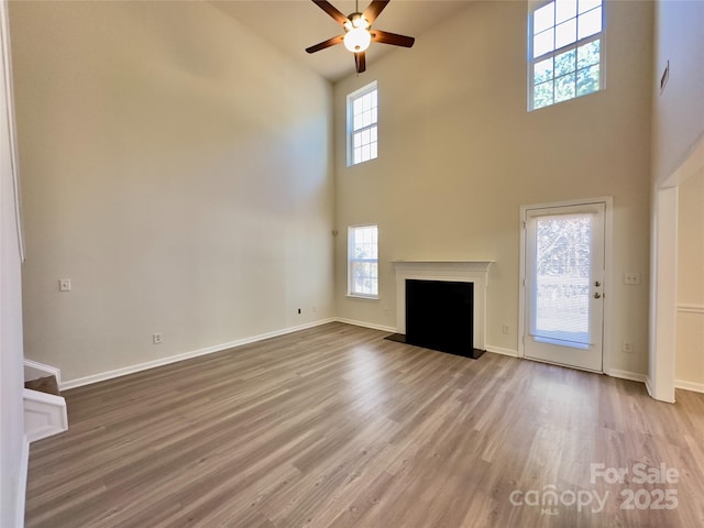 unfurnished living room featuring wood finished floors, a ceiling fan, and baseboards