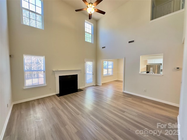 unfurnished living room featuring wood finished floors, a wealth of natural light, and ceiling fan