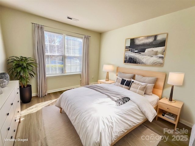 bedroom with visible vents, baseboards, and wood finished floors