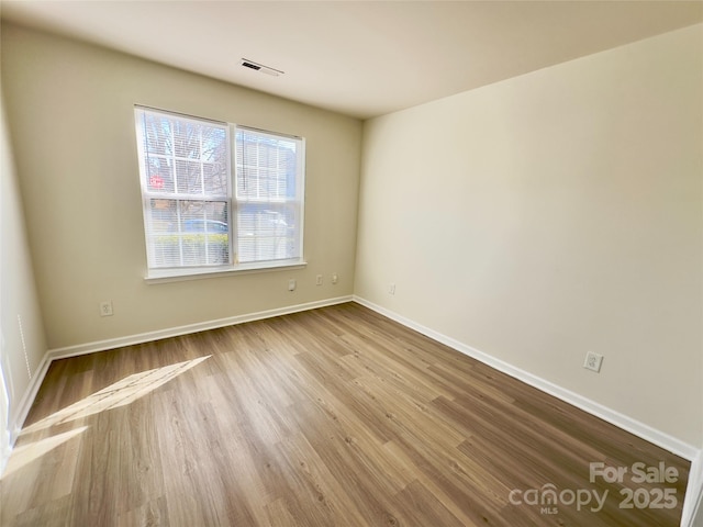 spare room featuring visible vents, wood finished floors, and baseboards