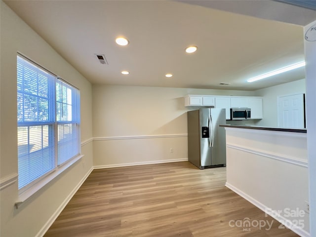 kitchen featuring baseboards, visible vents, stainless steel appliances, white cabinetry, and light wood-type flooring