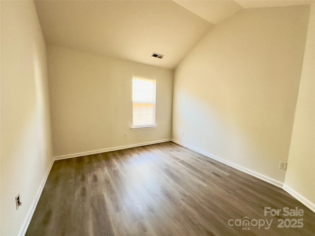 unfurnished room featuring dark wood finished floors, vaulted ceiling, and baseboards