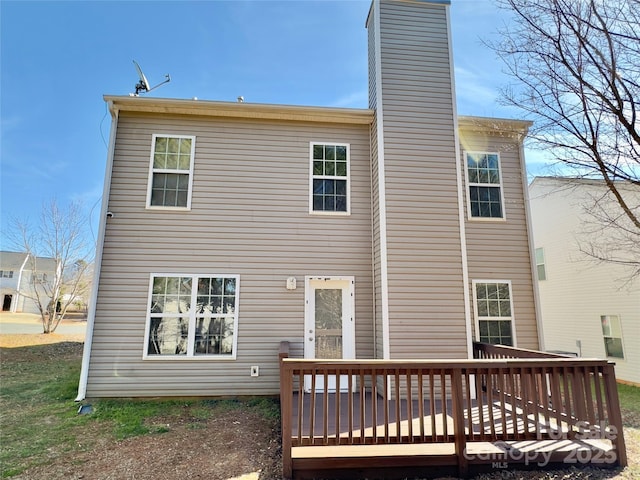 rear view of house featuring a wooden deck and a chimney