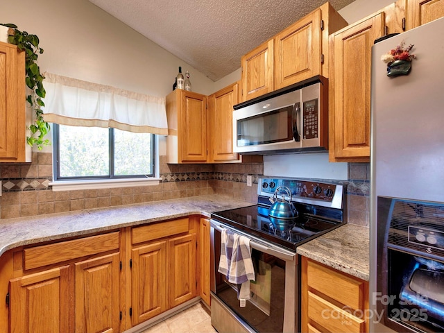 kitchen with light stone counters, tasteful backsplash, appliances with stainless steel finishes, and a textured ceiling