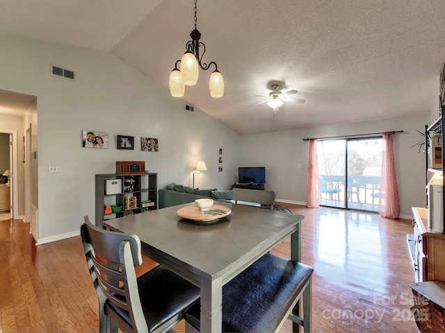 dining room featuring visible vents, ceiling fan with notable chandelier, lofted ceiling, and wood finished floors